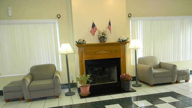 A room with two armchairs, a fireplace, and a checkered floor. - Fairfax Motel (Roanoke Rapids)