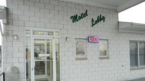 A motel with a white brick facade, a glass door entrance, and a neon 'OPEN' sign. - Fairfax Motel (Roanoke Rapids)