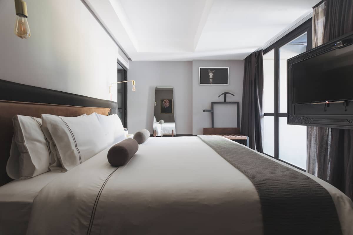 Habitación de hotel con una cama grande, televisor de pantalla plana, escritorio y ventana con cortinas.