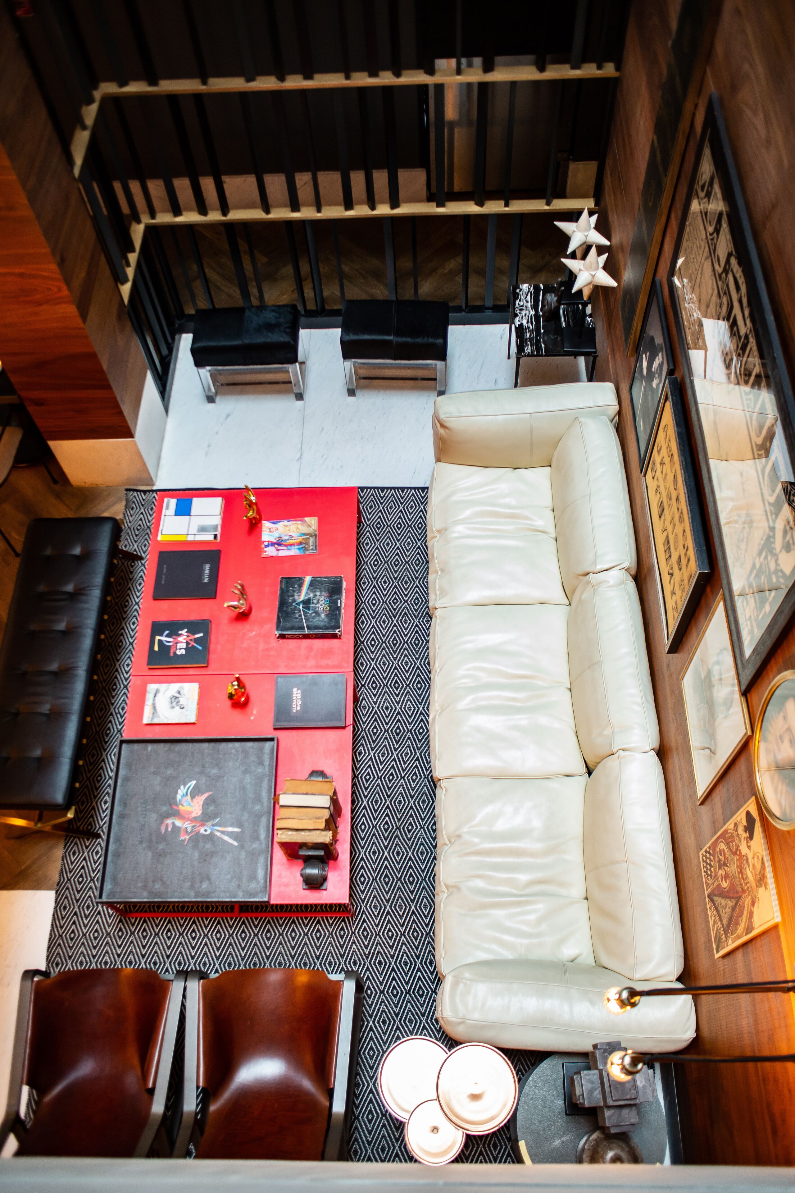 A modern living area with a sofa, a red coffee table with books, and a patterned rug.