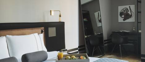Una habitación de hotel con una cama bien hecha, una bandeja de desayuno, un escritorio y un espejo grande.