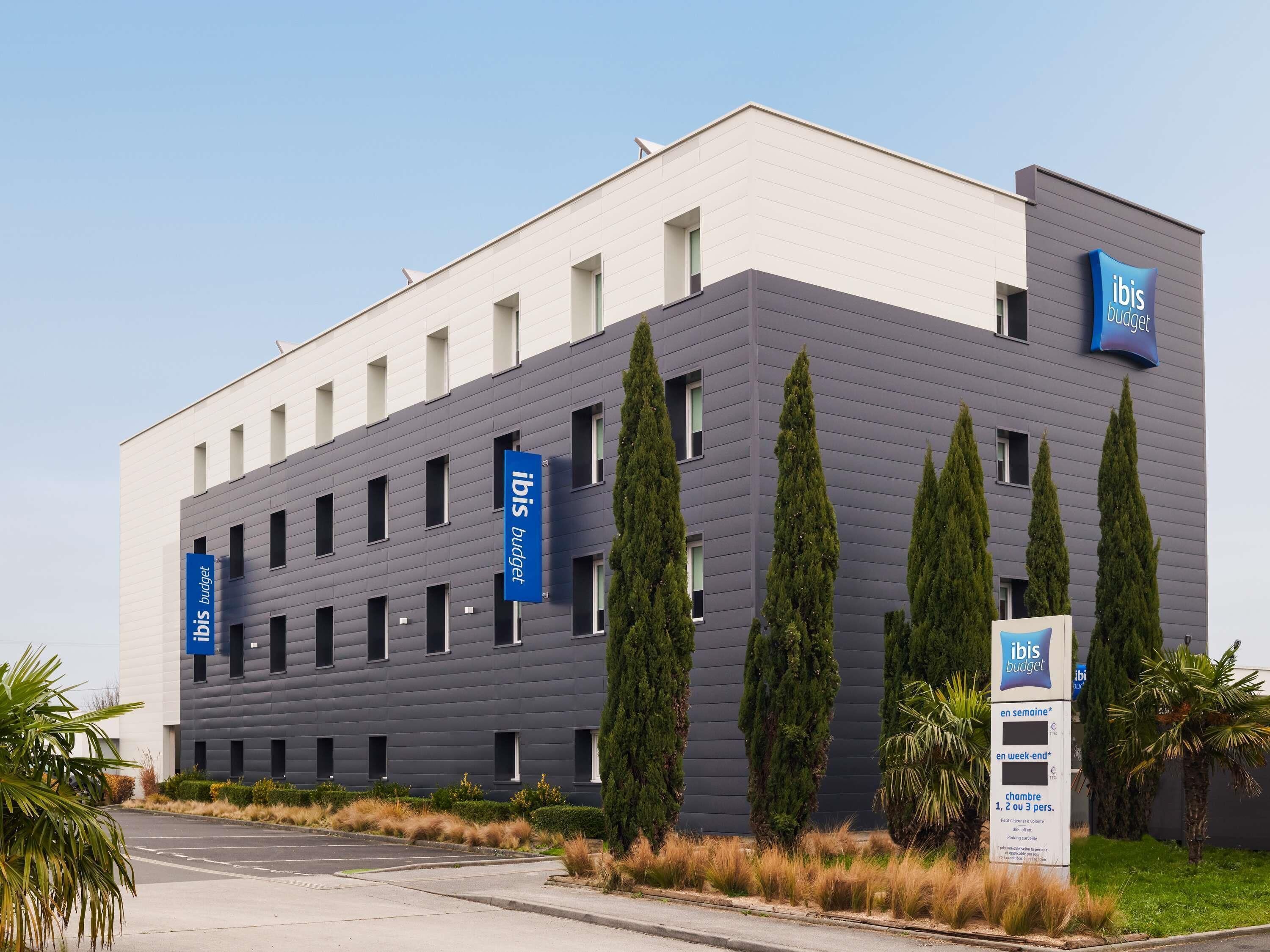 A modern building with multiple windows and a flat roof, featuring signage for 'ibis budget' and 'en semaine' accommodation options.