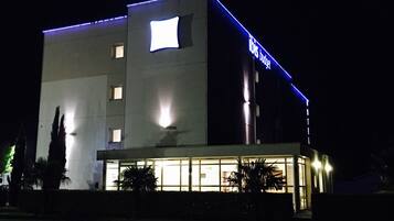 Ein modernes Hotelgebäude mit beleuchteter Beschilderung, einer glatten Fassade und einem gut beleuchteten Eingangsbereich.