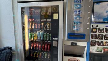 En automattankstation med ett stort utbud av snacks och drycker, inklusive en synlig soptunna märkt med texten ”Poubelle”.