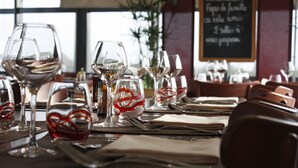 A restaurant table set with wine glasses, plates, and cutlery. - ibis budget Ancenis (Mesanger)