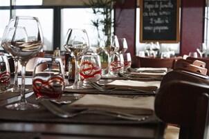Mesa de restaurante posta com copos de vinho, pratos e talheres.
