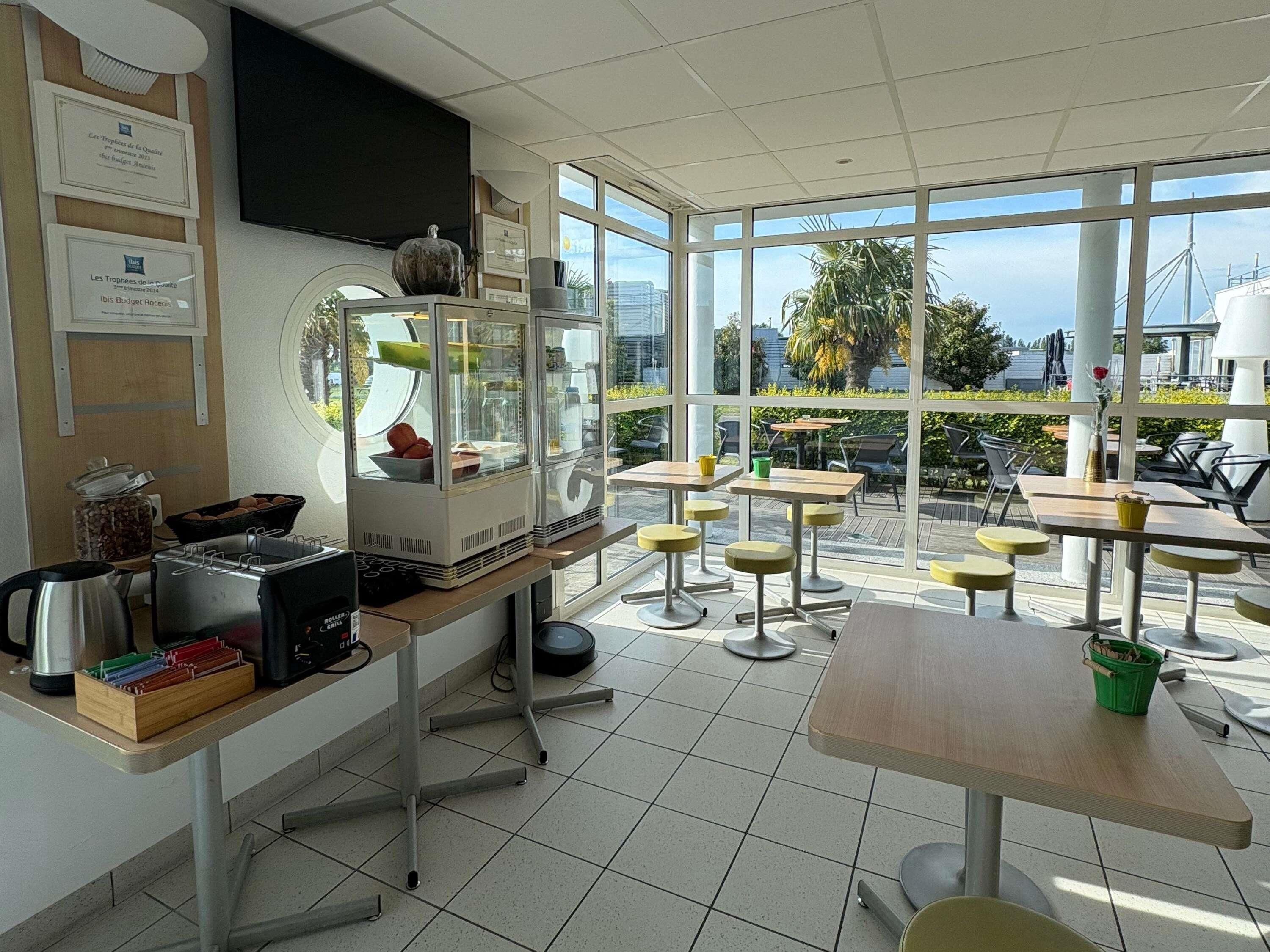A modern cafe with a large window, a coffee machine, and a display case with food items.