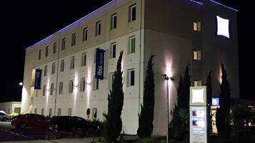 Un moderno edificio di hotel con diversi piani, illuminato da luci esterne.