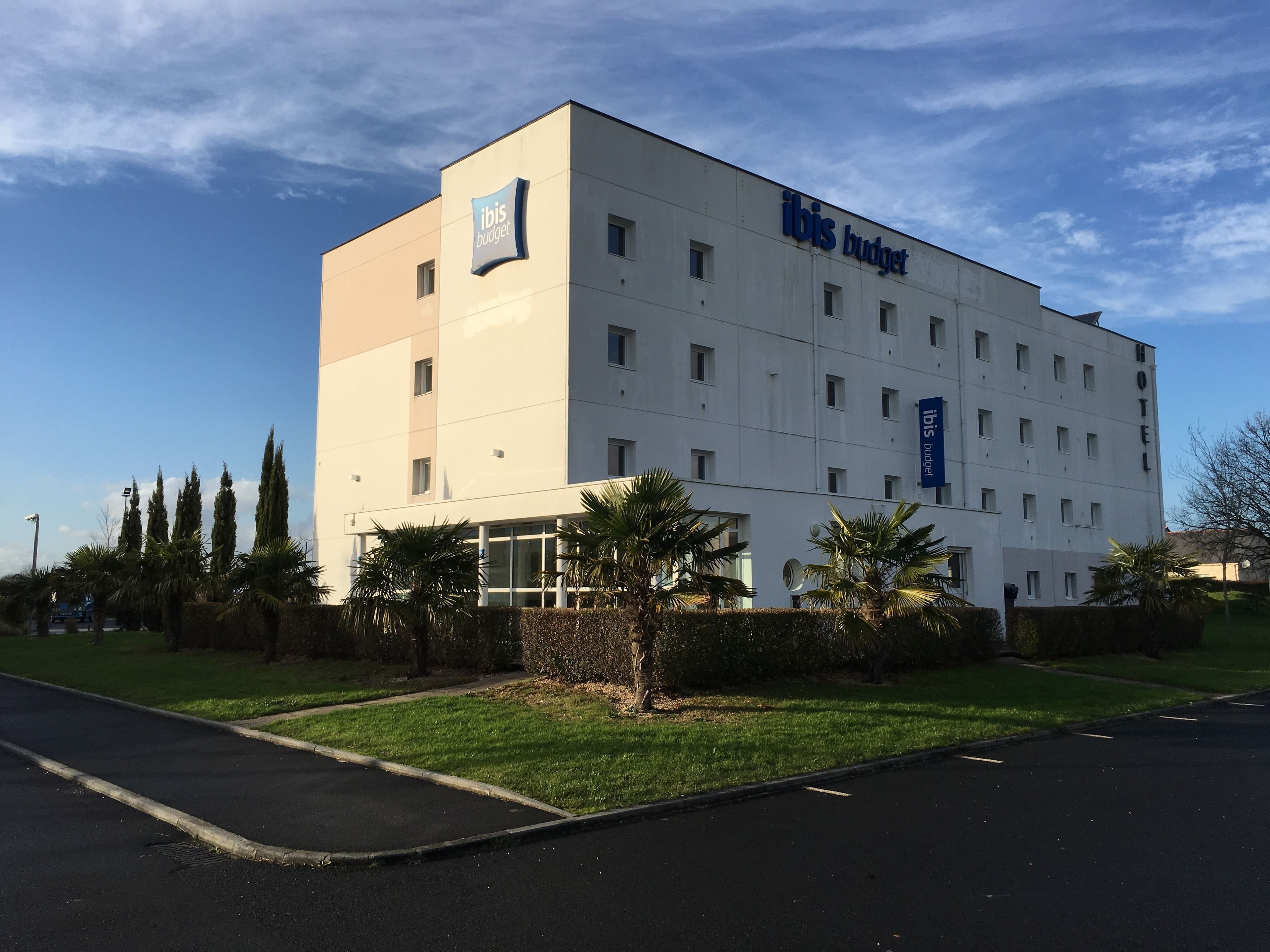 Un moderno edificio de hotel con fachada plana, múltiples ventanas y un letrero que dice 'ibis budget'.