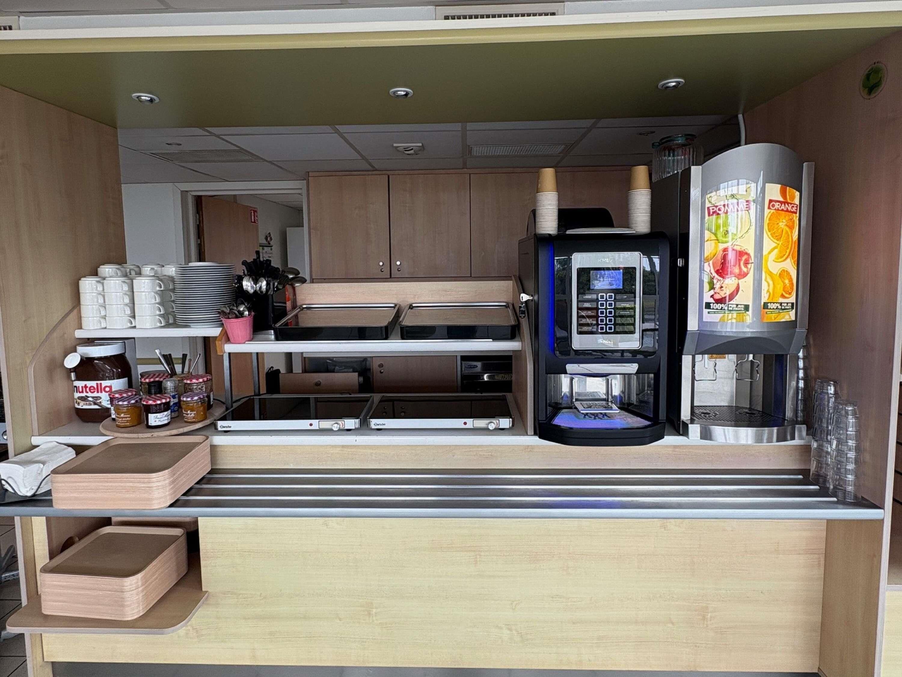 Une cuisine compacte équipée d’une machine à café, d’un petit réfrigérateur et d’un four à micro-ondes.