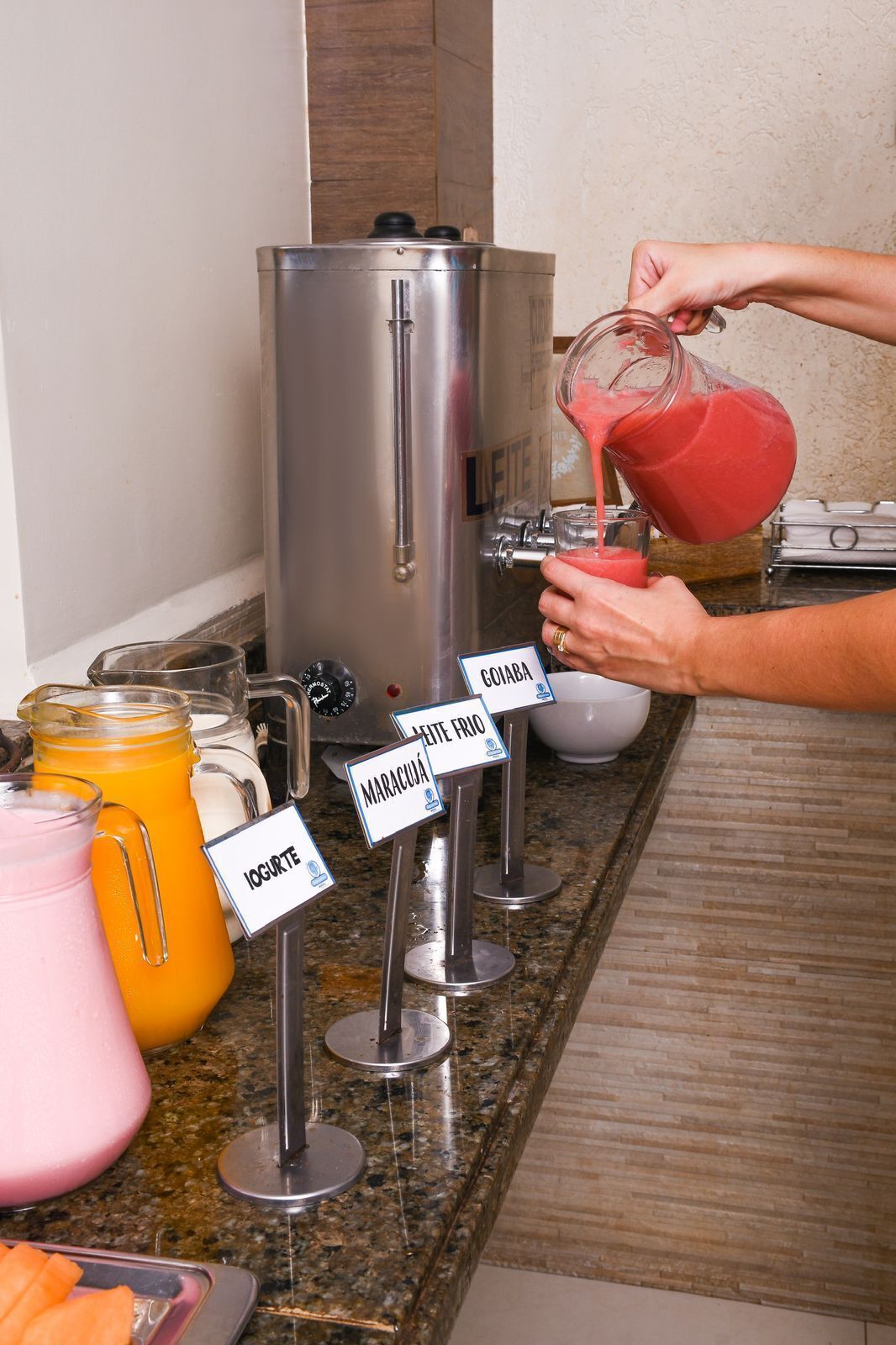 A beverage station with labeled dispensers for different drinks, including a pink smoothie and a yellow juice.