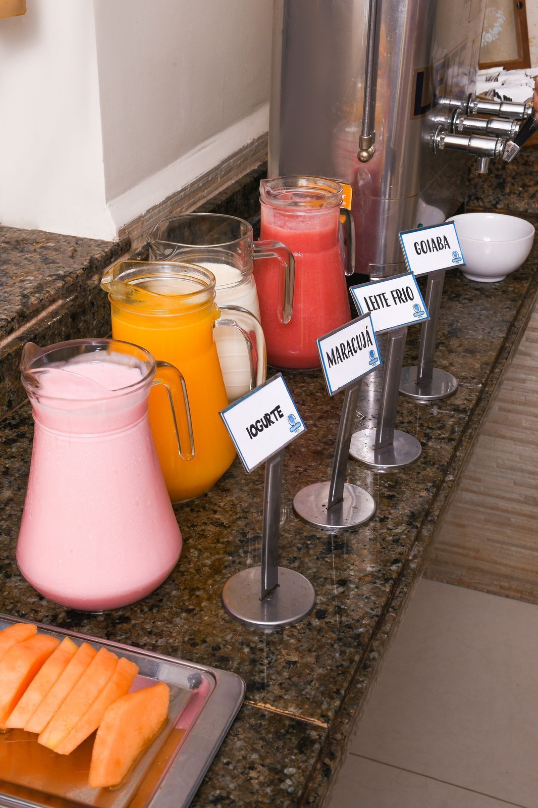 Un espace buffet proposant diverses boissons et une assiette de fruits coupés.