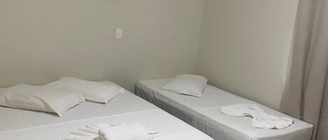 A hotel room with two beds, a painting on the wall, and a shower curtain.