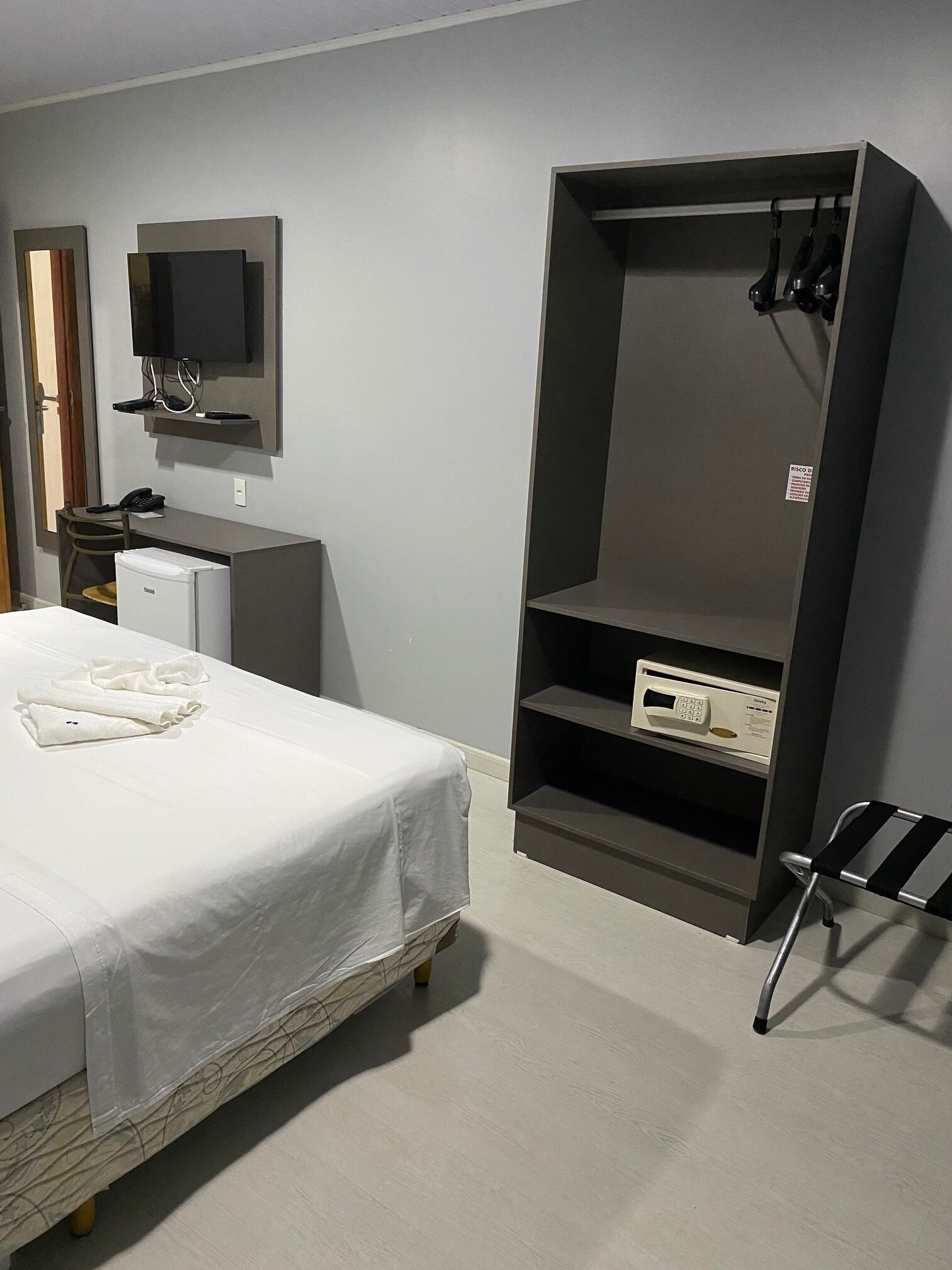 A hotel room with a bed, a desk, a television, and a wardrobe.