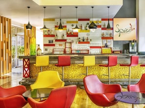 A restaurant interior with a bar area, red and yellow chairs, and a variety of bottles on shelves. - ibis Hyderabad Hitech City Hotel (Hyderabad)