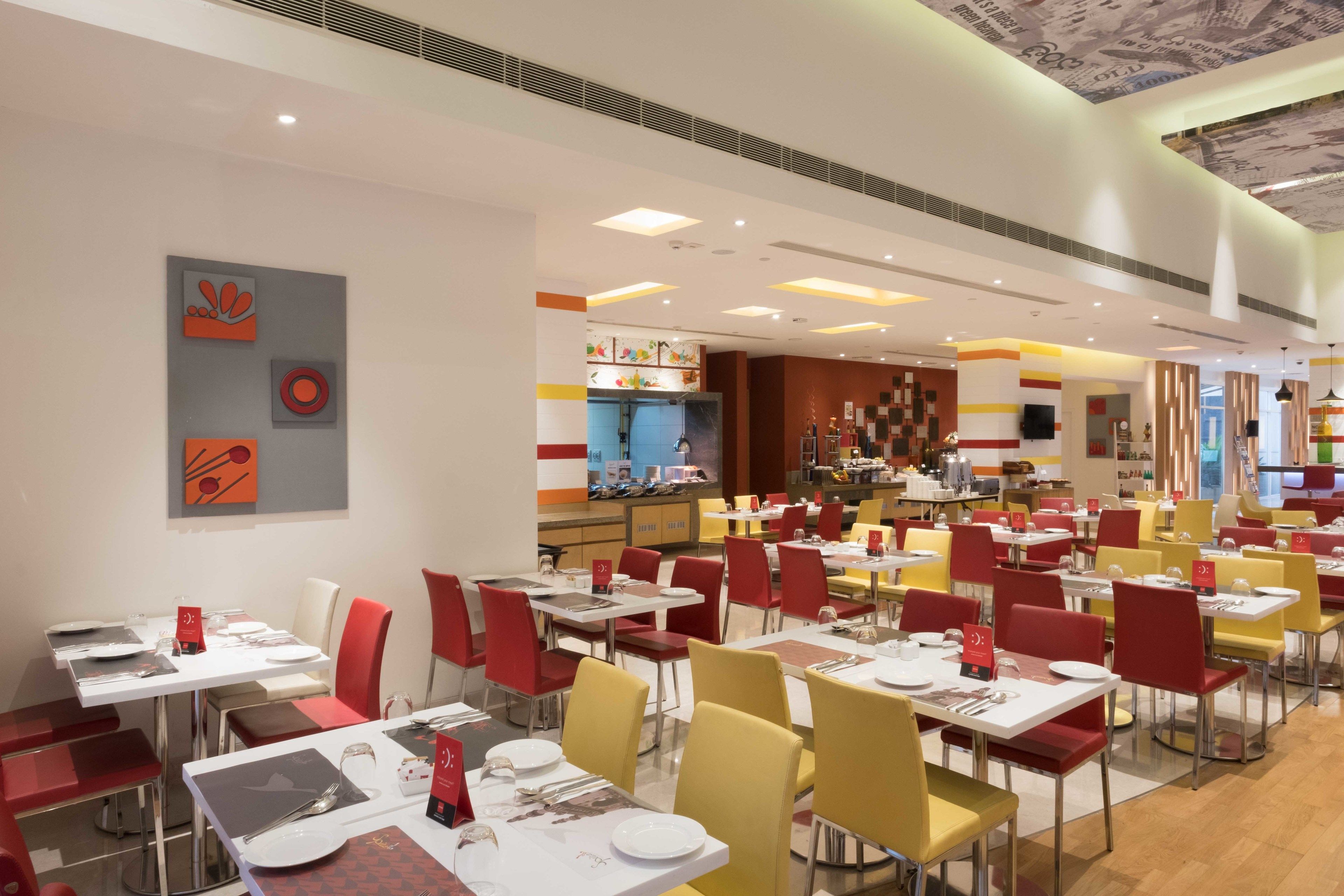 A spacious restaurant with multiple dining tables and chairs, a counter area, and a modern ceiling design.
