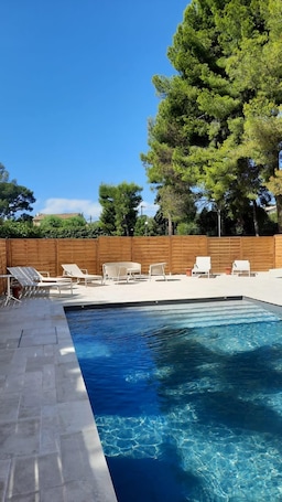 Una piscina al aire libre de temporada, sombrillas