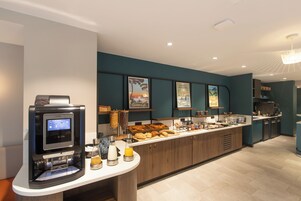 Una cocina moderna con una cafetera, varios productos de panadería y una barra para desayunos.
