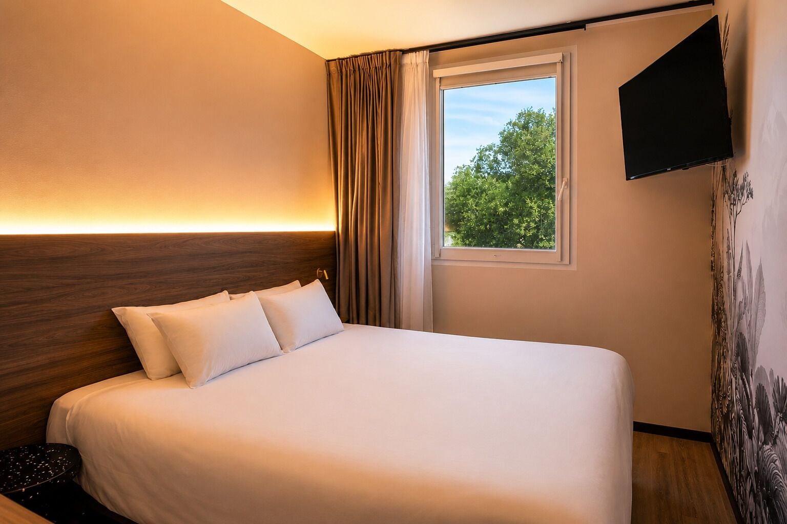 Ein Hotelzimmer mit einem großen Bett, einem Fenster mit Vorhängen, einem an der Wand befestigten Fernseher und einer Wand mit einem Wandgemälde zum Thema Natur.