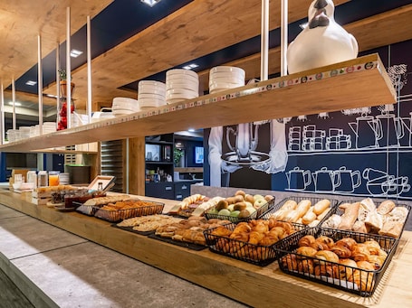 Un buffet de petit-déjeuner proposant un assortiment de pains, de viennoiseries et de fruits.. ibis budget Marne la Vallee Pontault Combault