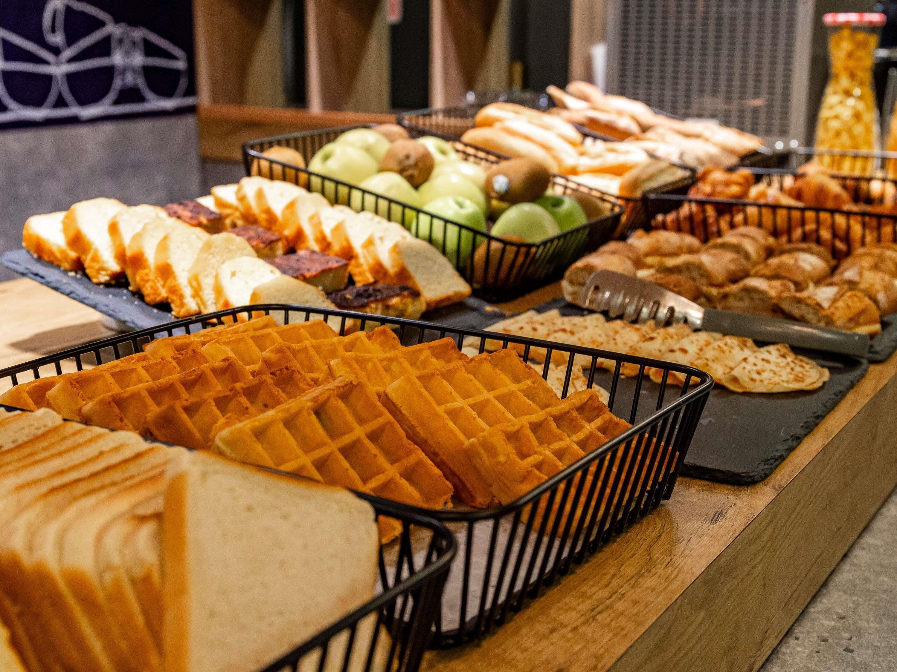 Ein Buffet mit verschiedenen Speisen, darunter Waffeln, Brot und Obst.