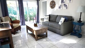 Ein Wohnzimmer mit einer Couch, einem Holztisch, einem Sessel und einer Lampe.