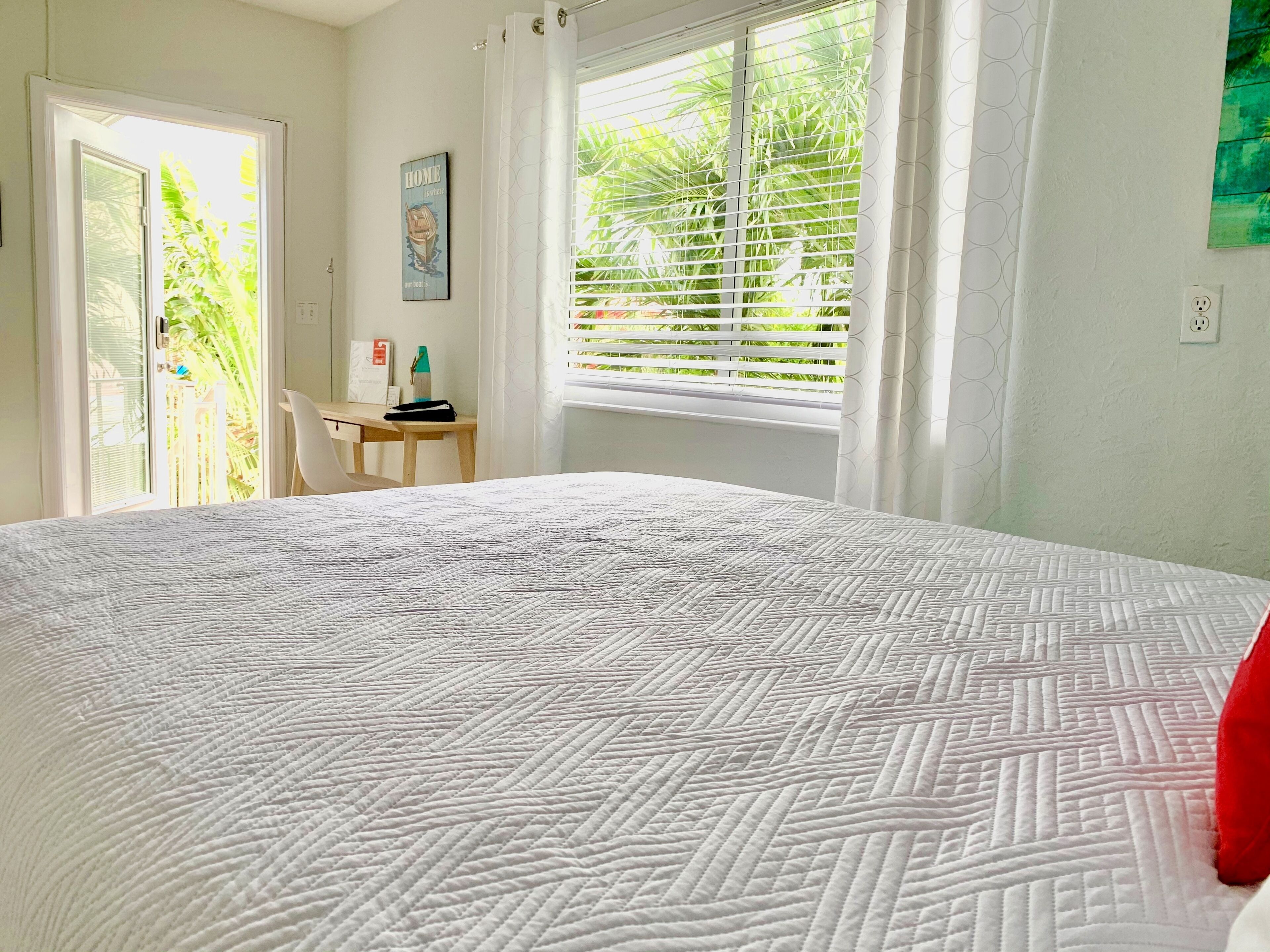 Un dormitorio con una cama grande, un escritorio y una ventana con persianas.