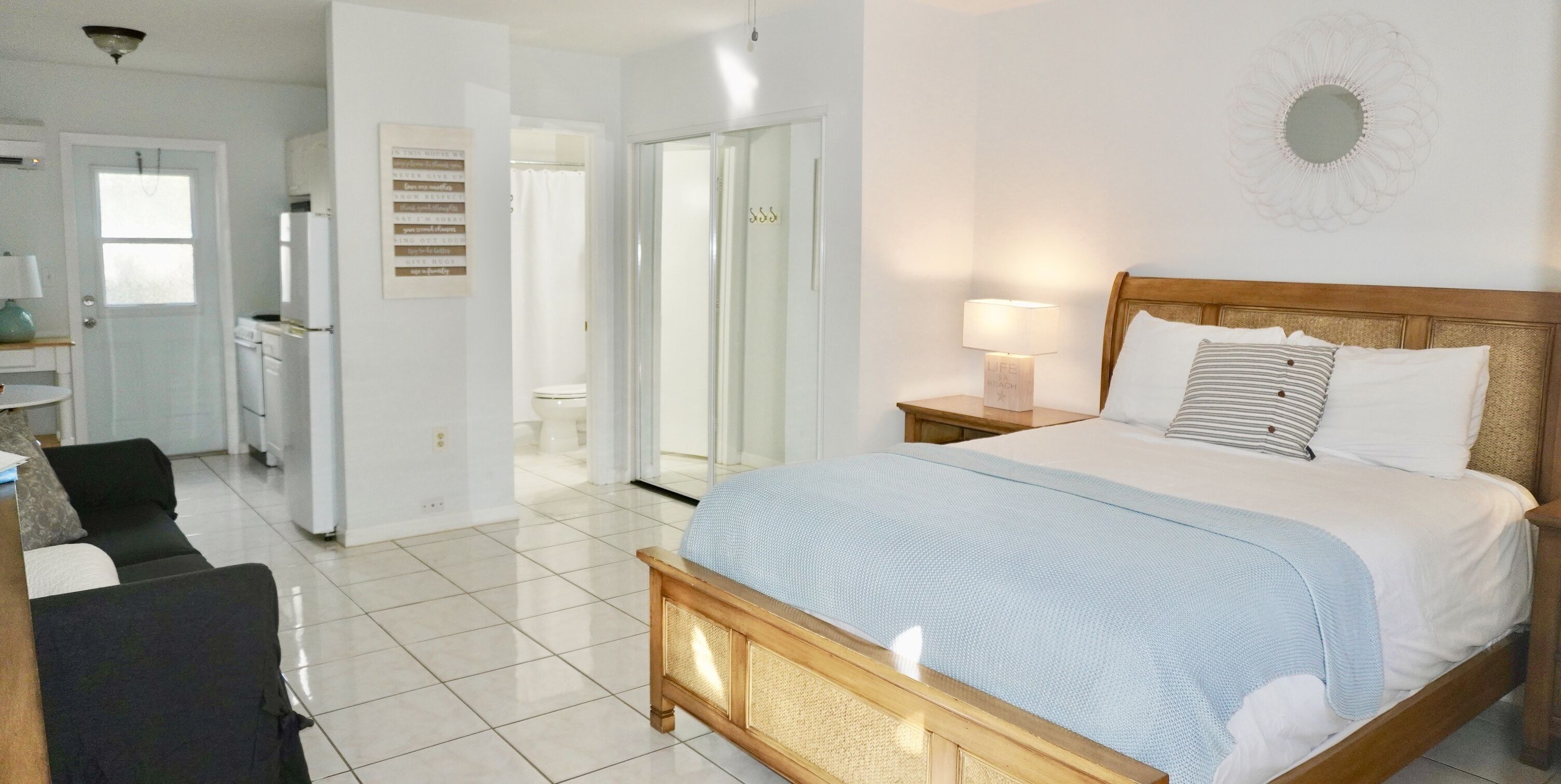 A bedroom with a bed, bedside table, and a view of the bathroom.
