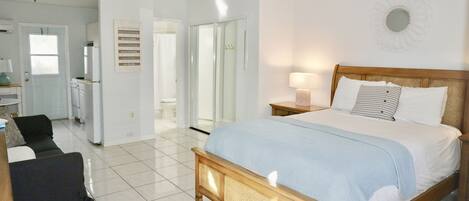 A bedroom with a bed, bedside table, and a view of the bathroom.