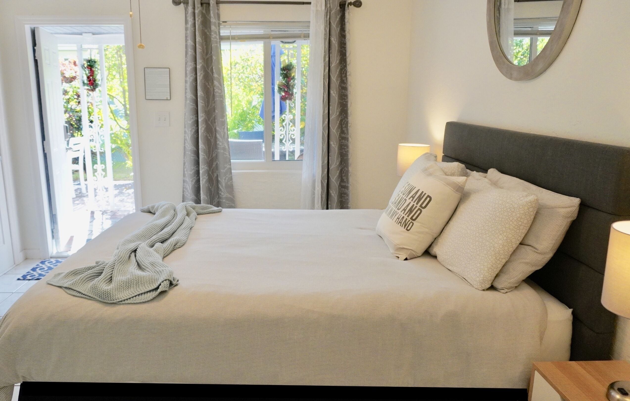 Un lit bien fait, avec une couverture et des oreillers, une lampe de chevet et une fenêtre avec des rideaux.