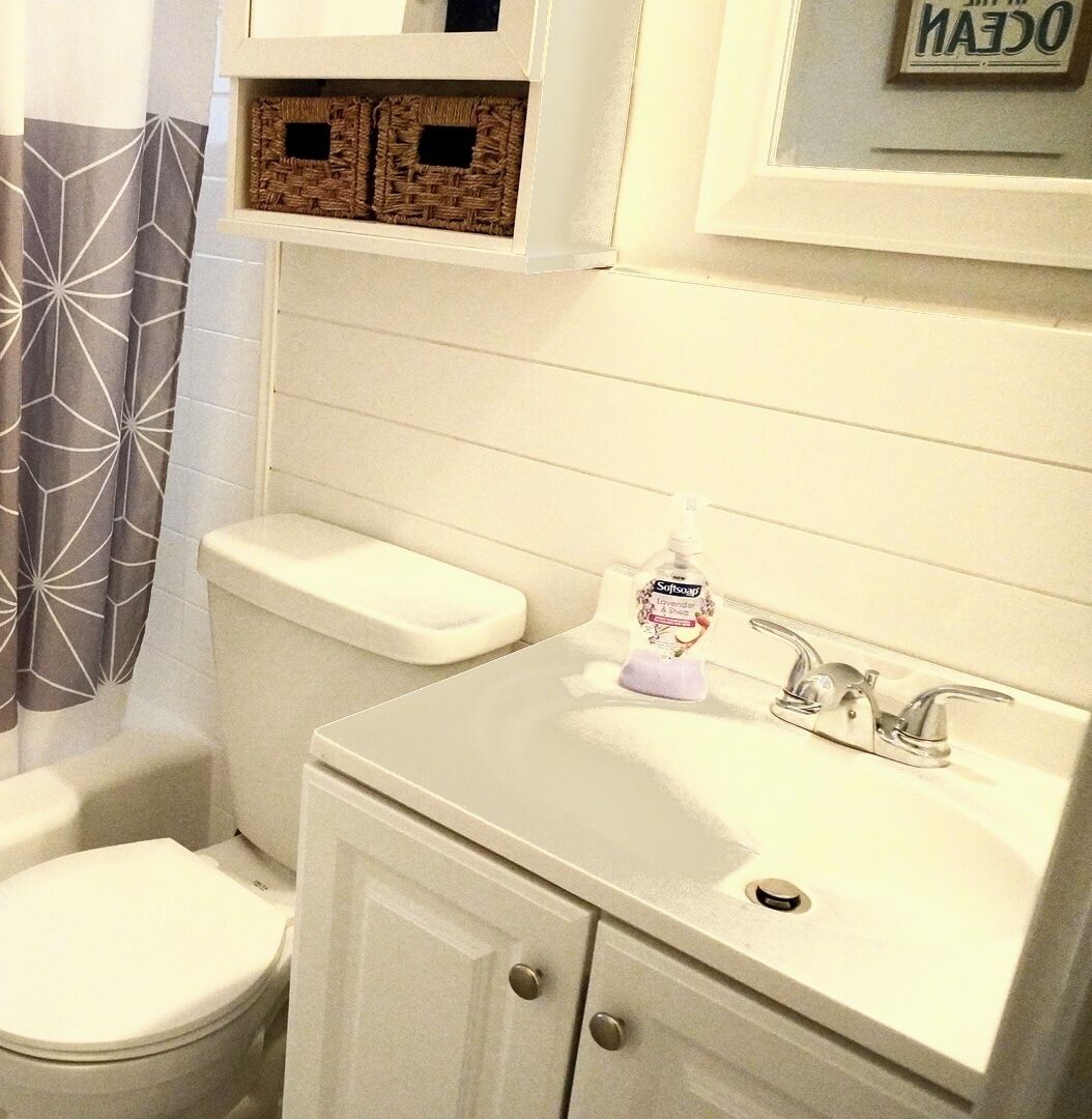 A bathroom with a toilet, bidet, and sink. There is a bottle of soap on the sink.