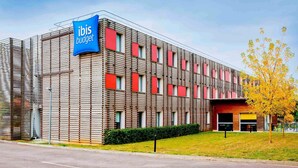Un edificio moderno con un llamativo letrero de “ibis budget”, que presenta una fachada tipo entramado y múltiples ventanas.