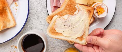 Ein Frühstücksteller mit Toast, Schinken, Käse und einem gekochten Ei.