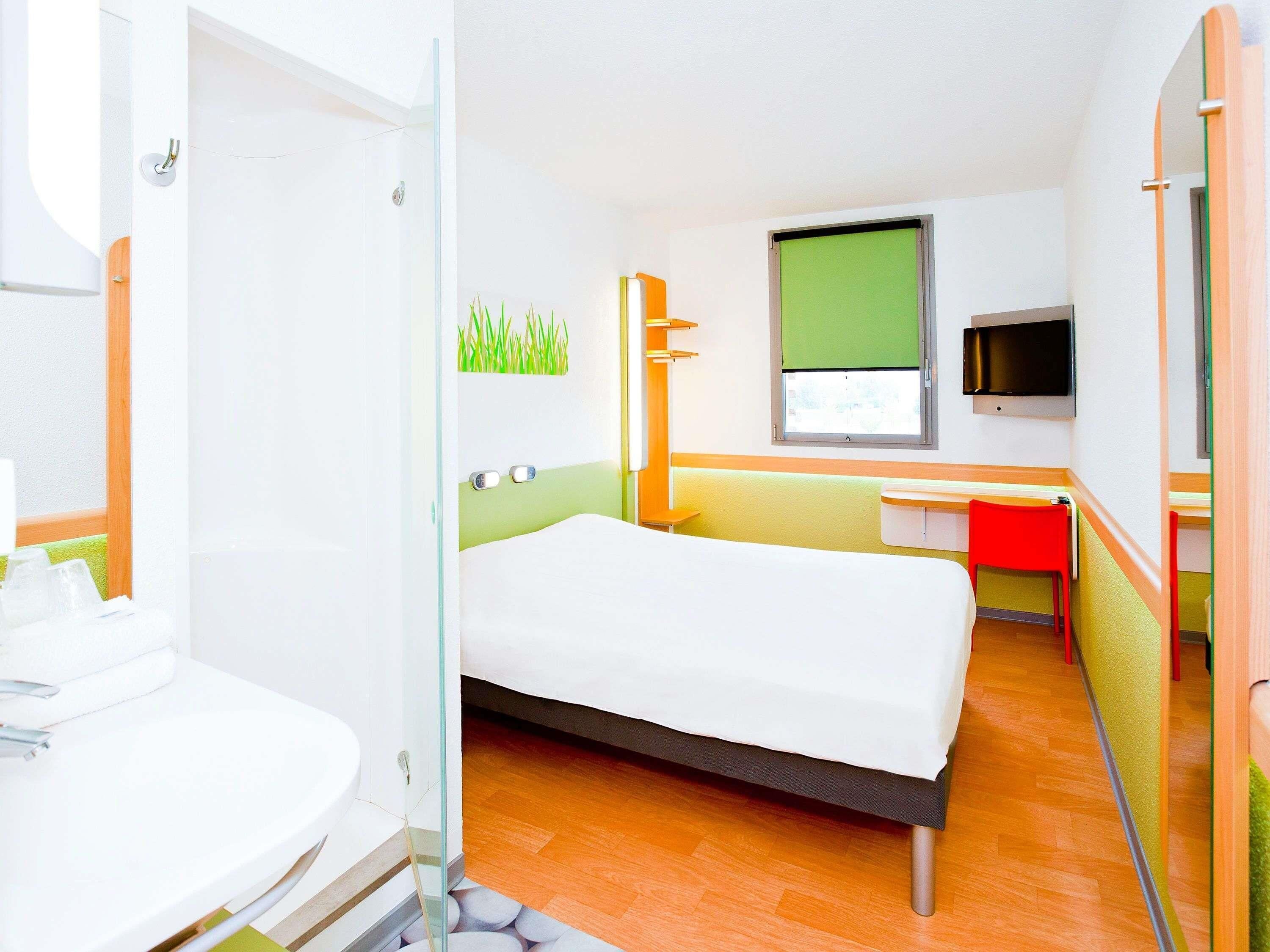 A hotel room with a bed, a TV, a desk, and a bathroom.