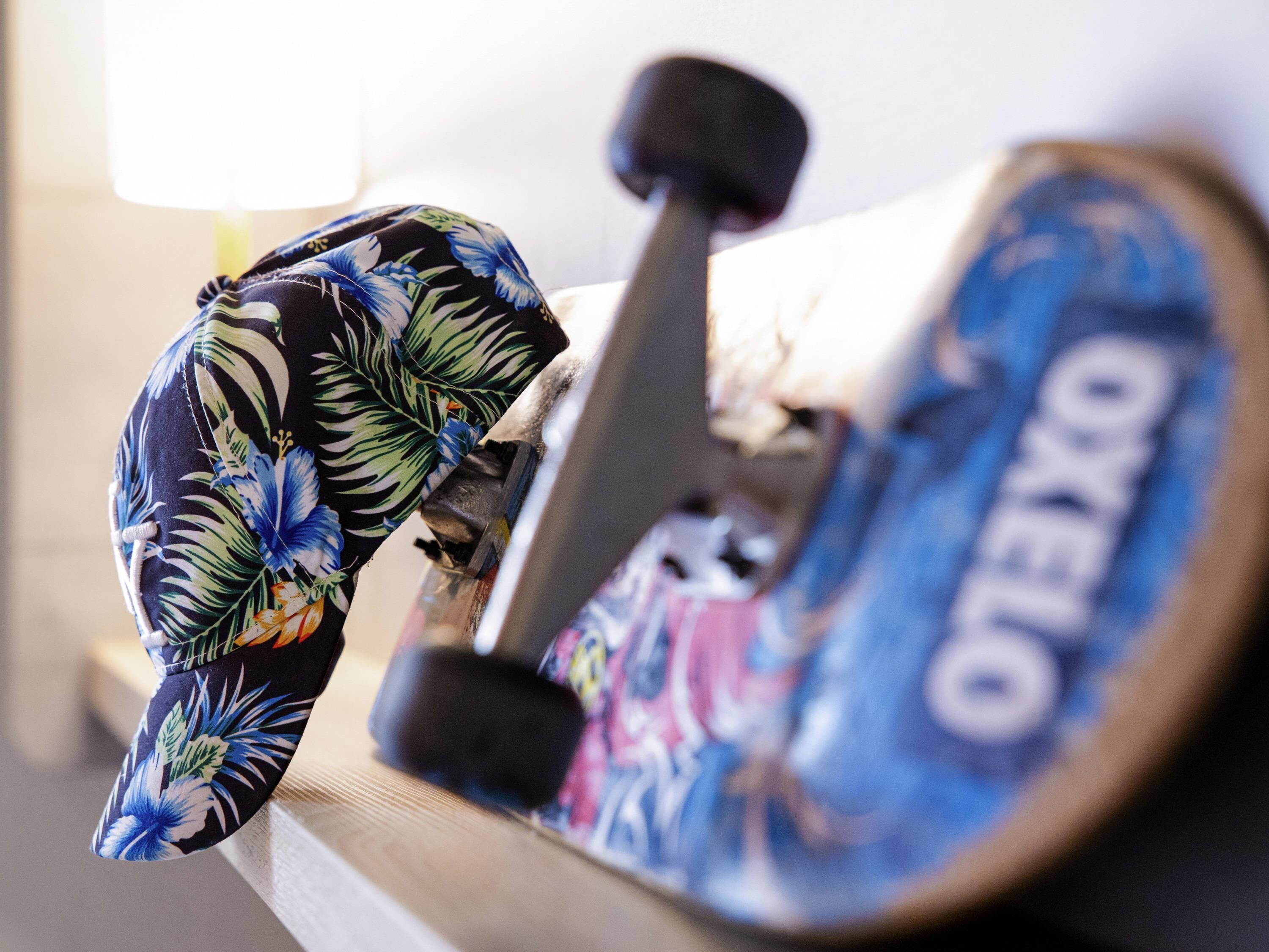 A skateboard with a colorful floral design and the word "OKELLO" on the wheel.