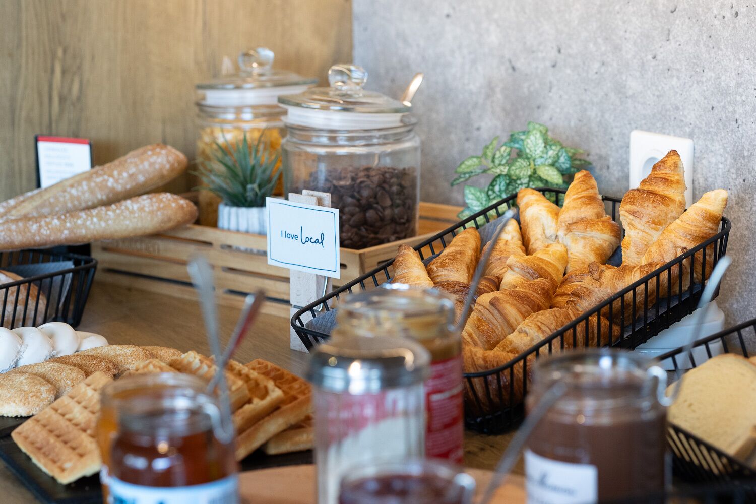 A breakfast buffet with various pastries, bread, and condiments.