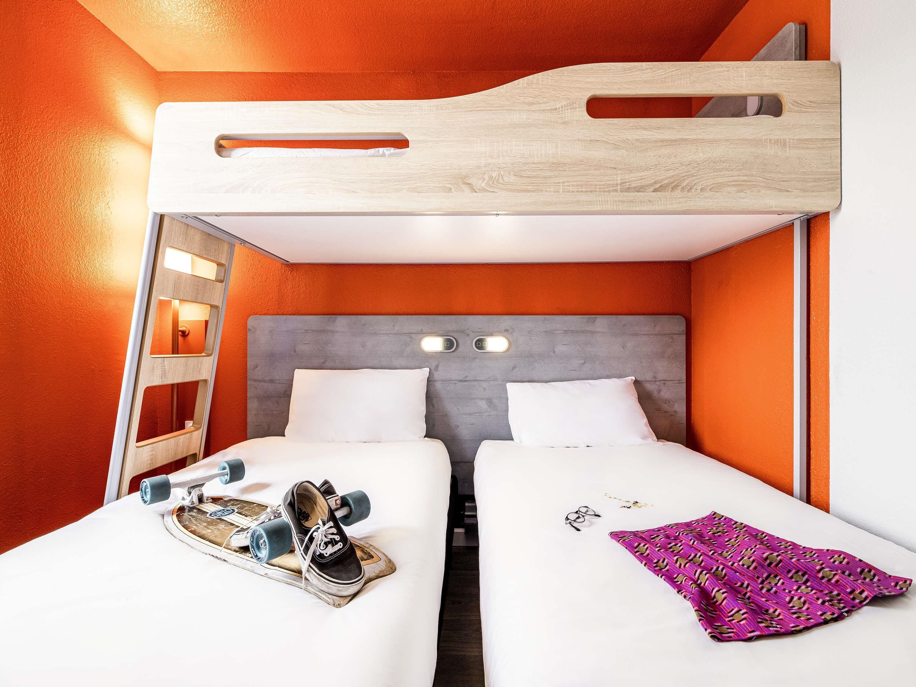 A bunk bed room with a wooden headboard, two beds, a small ladder, and a pair of shoes on the lower bed.