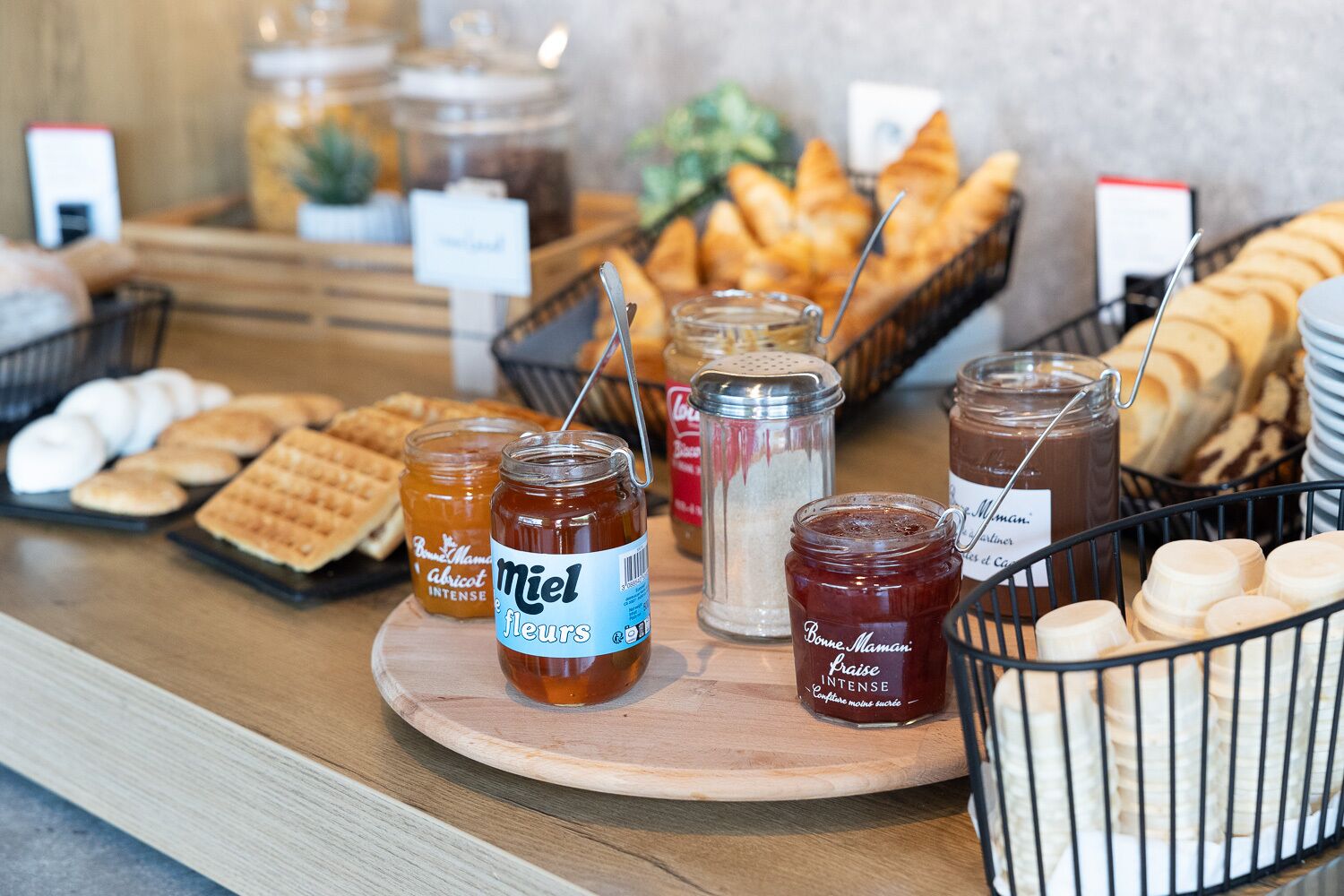 Ein Buffet mit verschiedenen Speisen, darunter Gläser mit Honig, Brot und Gebäck.