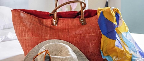 A red bag with brown handles on a bed.