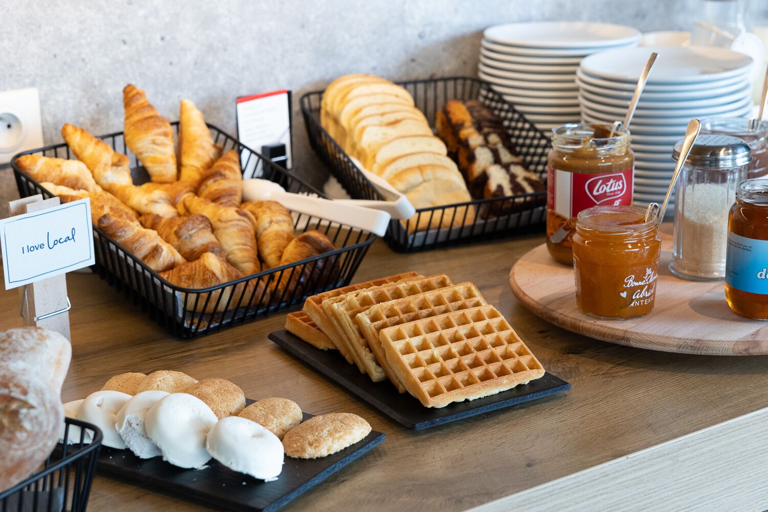 A breakfast buffet with croissants, waffles, and pastries.