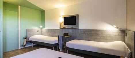 A hotel room with two beds, a TV, a desk, and a suitcase.