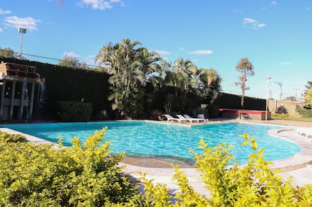 Una piscina al aire libre, una piscina con cascada, sombrillas