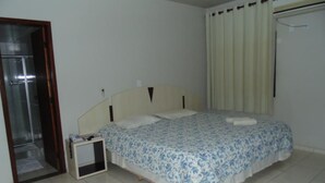 Makuuhuone, jossa on sänky, yöpöytä, ikkuna verhoilla ja ovi.