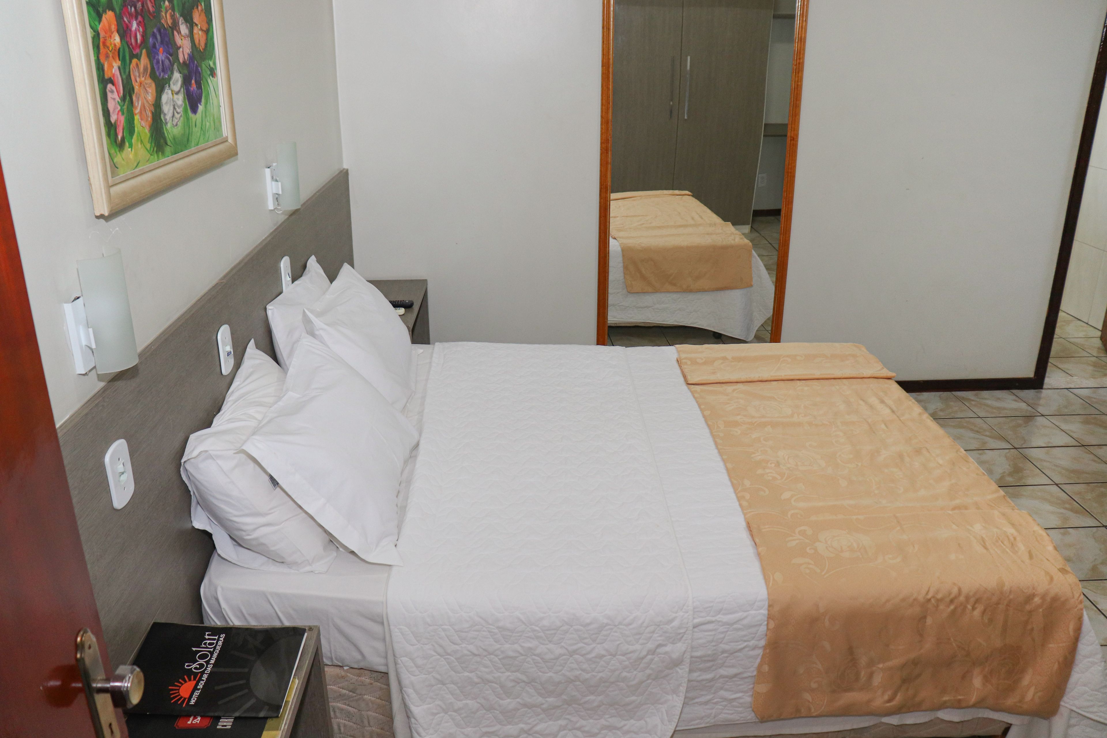 Une chambre d’hôtel avec un lit, une table de chevet, un tableau au mur et une porte.