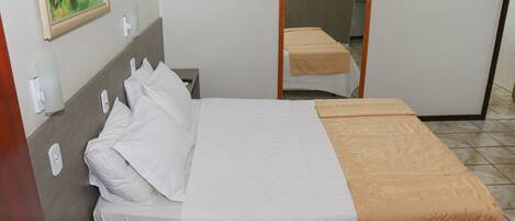 Une chambre d’hôtel avec un lit, une table de chevet, un tableau au mur et une porte.