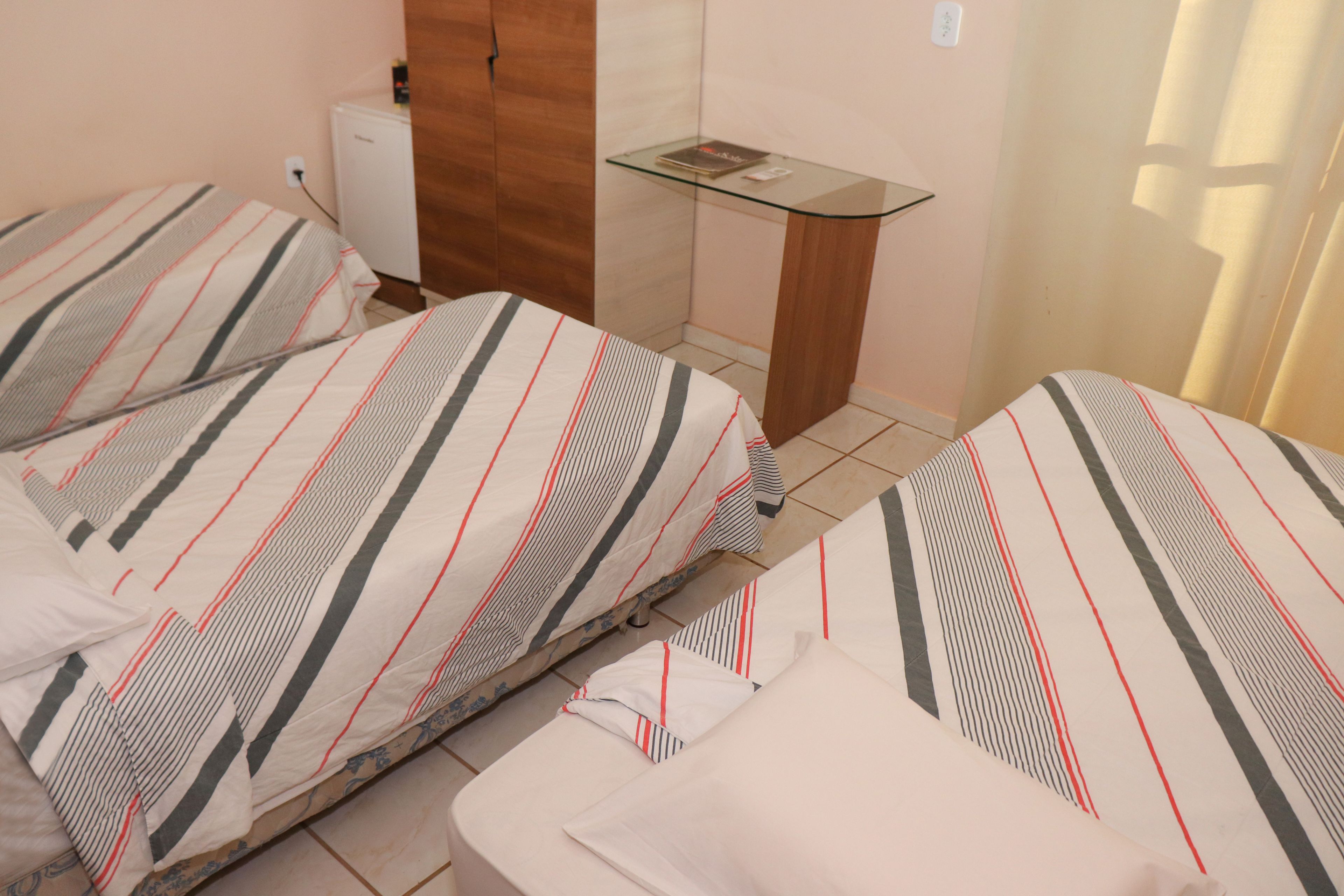 A hotel room with two beds, a small table, and a wardrobe.