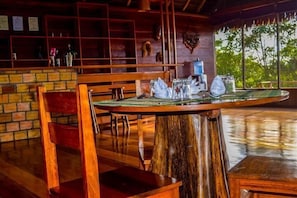 A wooden dining table with a rustic design, surrounded by wooden chairs. - Lakshmi Ecolodge and Holistic Spa (Nauta)