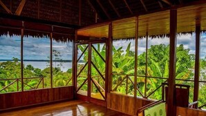 A room with wooden walls and a large window overlooking a lush landscape. - Lakshmi Ecolodge and Holistic Spa (Nauta)