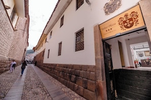 A cobblestone street with a building featuring a signboard with a coat of arms and the name 'Yabar Plaza.'