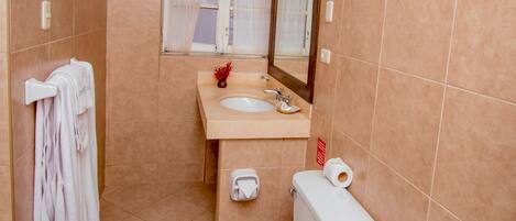 A bathroom with a toilet, sink, and mirror.
